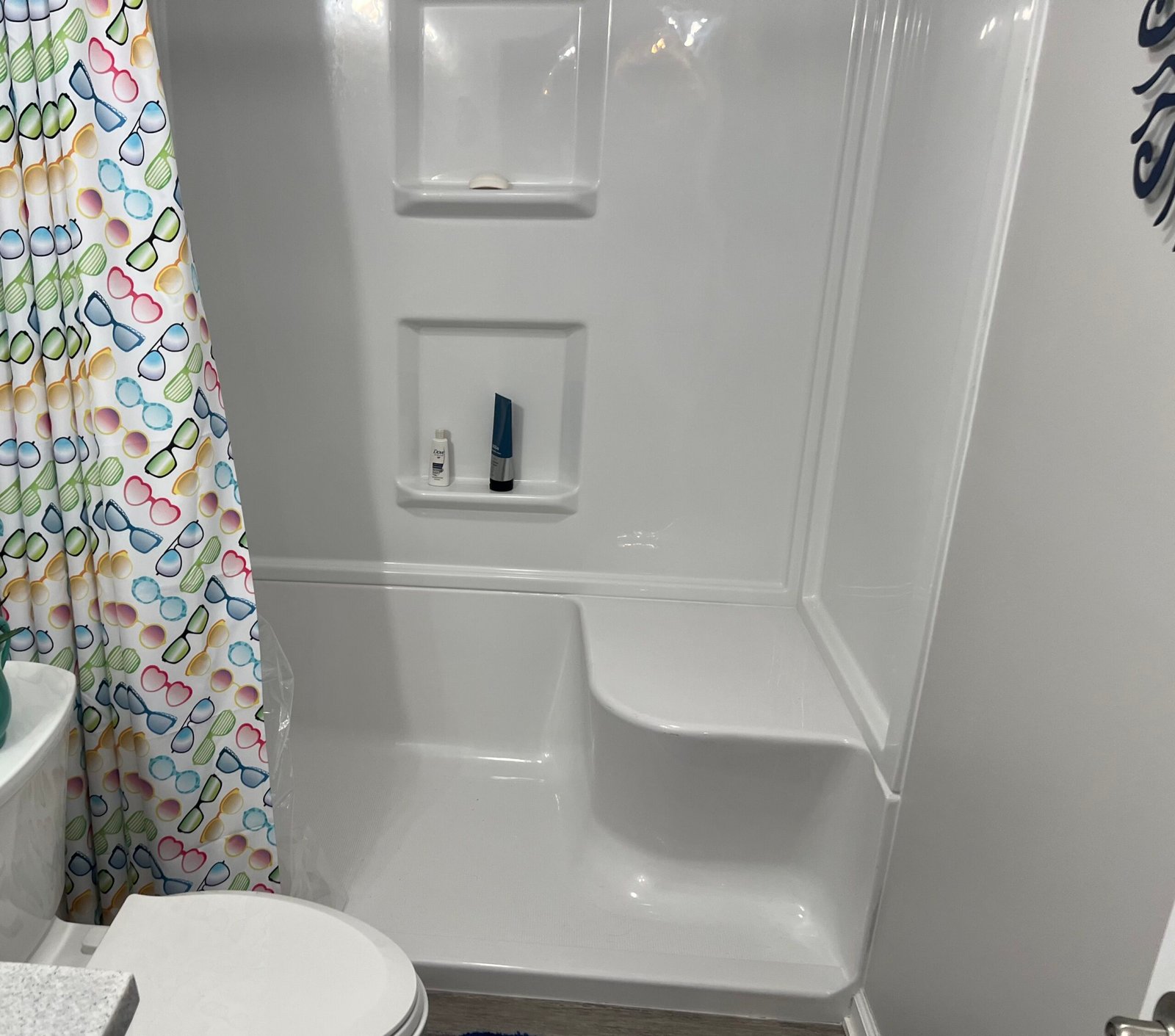 White walk-in shower with molded seat and recessed shelves in a remodeled bathroom