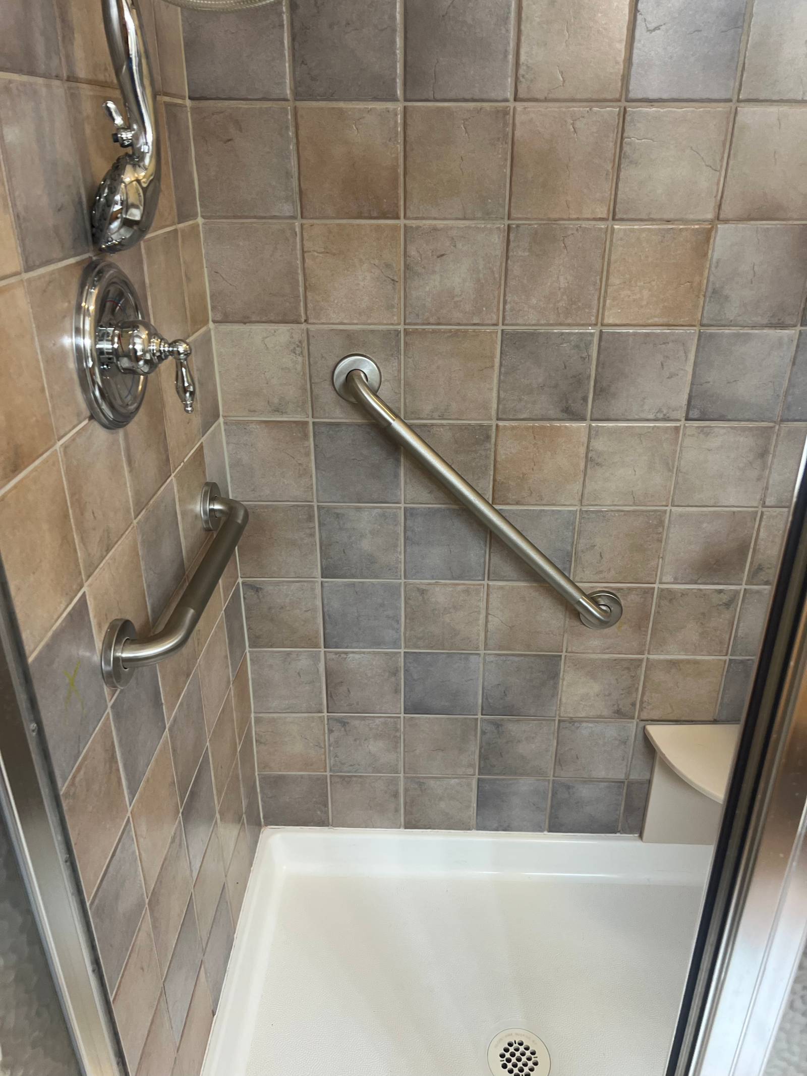 Two stainless steel grab bars installed in a tiled Columbus shower